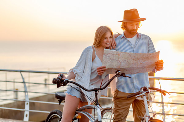 attractive-happy-couple-of-friends-traveling-in-summer-on-bicycles-man-and-woman-with-blond-hair-boho-hipster-style-fashion-having-fun-together_web