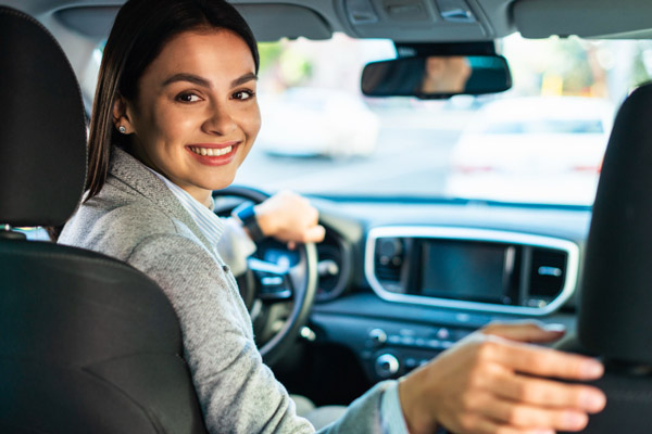 smiley-businesswoman-turning-around-in-the-car_web